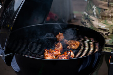 Process of cooking meat on grill with smoke at summer local food market - close up. Outdoor...