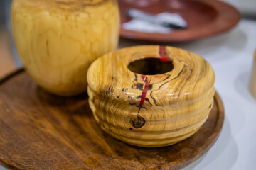 Handmade carved wooden kitchen utensils, plates, decor on counter of craft fair, trade show - close up. Handcraft, woodwork and carpentry concept