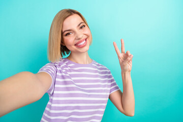 Selfie photo cadre of friendly charming lady wear trendy t-shirt show v-sign toothy beaming smile isolated on aquamarine color background