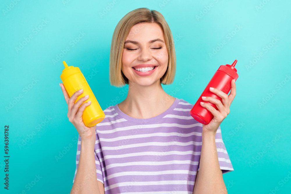 Sticker Photo of cheerful funny person bob hairdo trendy t-shirt cooking burger hold bottles of ketchup isolated on turquoise color background