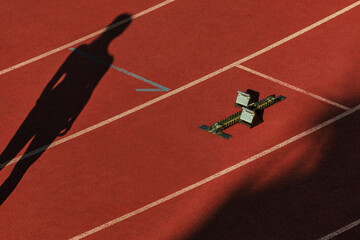 black silhouette female athlete on red track stadium, start race and starting blocks