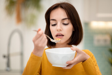 Closeup of young woman enjoying healthy breakfast at home