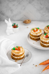 Easter Carrot cake with cream cheese frosting and marzipan decorations on a white stone background for festive dinner. Small easter bento cake. Fresh homemade carrot cake. Traditional Easter food.