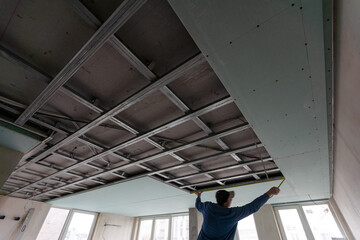 Obraz na płótnie Canvas Workers fitting panel into frame of ceiling.