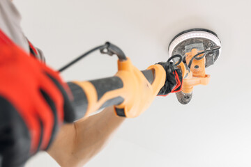 Man worker Painter work with white ceiling polishing and sanding surface after putty for painting