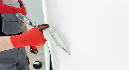 Master builder applies white plaster on spatula. Repair of apartment, leveling walls with putty © Parilov