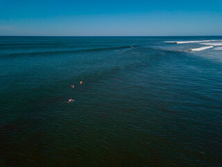 A pack of three surfers swim toward the tube waves crashing in Punta Roca, El Salvador