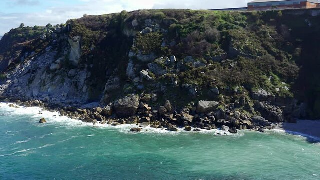 Panoramic view of a cliff in the Cantabrian Sea with houses on the edge of the precipice, Asturias, Spain.