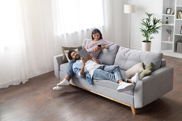 High angle view relaxed eastern lovers using gadgets at home
