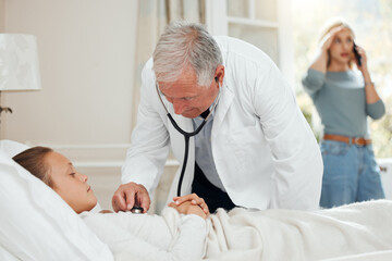 Fototapeta premium Like education, healthcare also needs to be given importance. Shot of a mature doctor listening to a little girls heartbeat during a checkup at home.