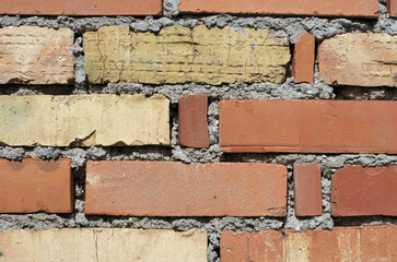 wall made of bricks of various colors. gray cement joint.