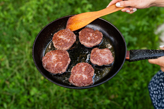 Fried patties in a pan. Rural menu. Traditional village food. Top view of a frying pan, a woman turns the patties with a spatula.
