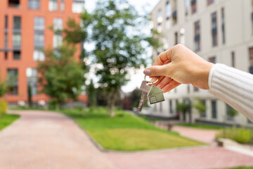 Hand holding keys on the background of a new building, construction concept. Buying real estate,...