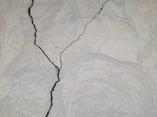 Cracked concrete wall covered with gray cement mortar. Destruction caused by an earthquake. Large...
