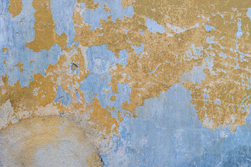 The texture of old, cracked, peeling walls. The background is blue and yellow walls