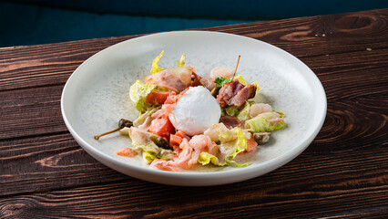 Fresh salad with egg, bacon, capers, tomatoes and lettuce.