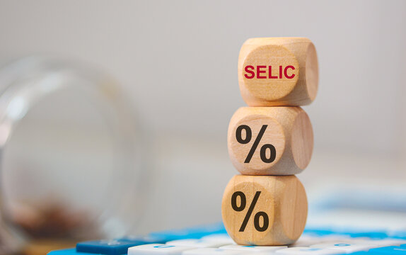 SELIC. A sigla selic e o s&iacute;mbolo de porcentagem em dados de madeira que est&atilde;o sobre uma calculadora. Economia Brasileira.