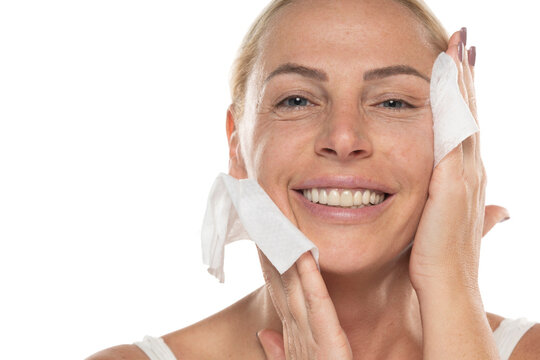 Portrait of a senior woman clean her face with wet tissues on a white background
