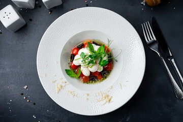 Italian caprese salad with cherry tomatoes, mozzarella cheese, basil, olives and spices.
