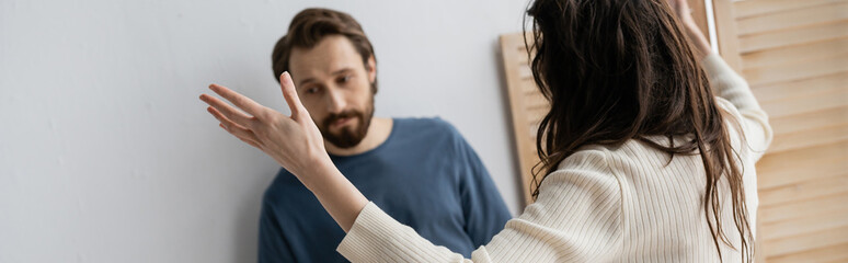 Brunette woman quarrelling with sad blurred boyfriend at home, banner.