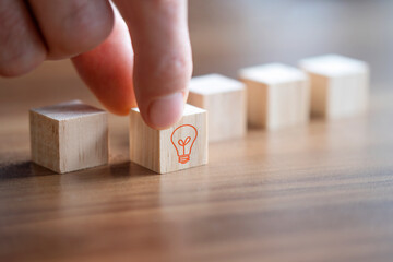 Businessman holding wooden block with light bulb on it, idea concept.