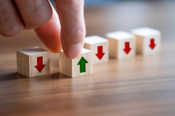 Men holding a wooden block with green up arrow on it. Moving forward business concept.