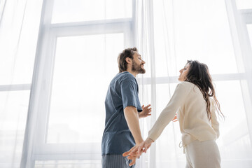 Fototapeta premium Low angle view of couple in pajama arguing during breakup at home.