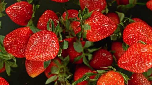 Super slow motion of rotating strawberries on black background, top view. Filmed on high speed cinema camera, 1000 fps, placed on high speed cine bot.