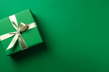 Gift box with satin ribbon and bow on green background. Holiday gift with copy space. Birthday or Christmas present, flat lay, top view. Christmas giftbox concept