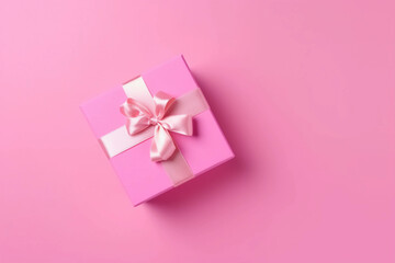 Gift box with satin ribbon and bow on pink background. Holiday gift with copy space. Birthday or Christmas present, flat lay, top view. Christmas giftbox concept