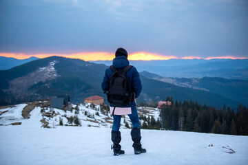 tourist in the mountains at dawn, looking into the distance.