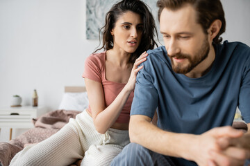 Obraz premium Brunette woman in pajama calming down upset blurred boyfriend on bed.