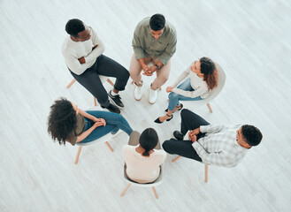 Group therapy is a must. High angle shot of an unrecognisable group of people sitting together and talking during therapy. - Powered by Adobe