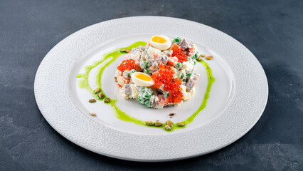 Salad Olivier from boiled potatoes, carrots, green peas, cucumbers, eggs, chicken ham, mayonnaise served with red caviar and quail eggs.