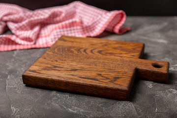 Fototapeta premium Cutting board over towel on wooden kitchen table. Cutting board and kitchen towel on black textured background. Menu food card or recipes background concept.MOCKUP. Design. Place for text, copy space.
