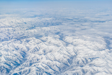 Aerial view of the Siberian hills and mountains covered with snow in the tundra. Siberia, Far East of Russia. Snow-covered tundra in the Arctic.