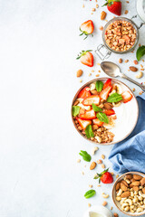 Yogurt with granola, nuts and strawberries on white. Healthy snack or breakfast, fruit salad. Top view with copy space.