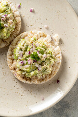 Healthy snack. Rice cake with avocado and tuna salad with red onion.