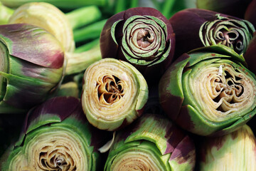 Fototapeta premium Close up of organic peeled artichokes in a box at outdoor farmers market. Cynara cardunculus var. Scolymus. Vegan food and healthy nutrition concept. Artichoke heart for sale in the street of Italy.