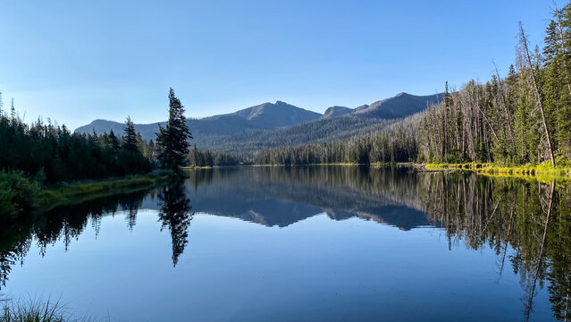 Sylvan Lake morning reflections of the trees and mountains in Yellowstone National Park © Kurt