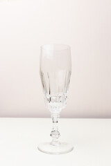 Empty crystal glass in front of beige background. Minimal concept.