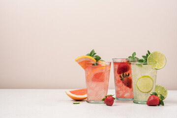 Strawberry, mojito, grapefruit lemonade with ice on beige background. Summer refreshing drinks