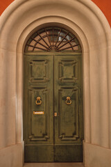 Vintage brown green wooden door with orange wall in Italy. High quality photo