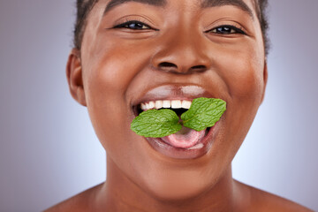 Minty fresh breath. Studio shot of a beautiful young woman posing with mint leaves in her mouth. © Alexis Scholtz/peopleimages.com