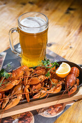 Boiled crayfish with lemon, dill and herbs on a wooden cutting board on blue wooden background. Crayfish dish