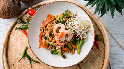 Udon noodles stir fry with shrimp, chicken, carrots, onions, broccoli, sweet peppers and green sprouts.