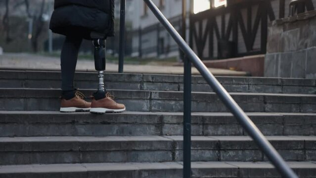 Adaptive stair climbing, Limb replacement, Climbing diversity. Stairs on city street climbed by man who has prosthetic leg and is disabled.