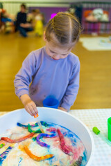 Little girl dripping water on colorful paper worms. Sensory development and experiences, themed activities with children, fine motor skills development