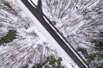 Aerial view on road in winter time, road surrounded with forest trees. Rural winter area. Top view...