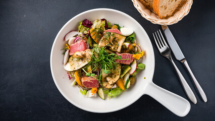 Salad with tuna, radishes, eggplant, cucumbers, eggs, tomatoes, red onions, olives, lettuce and herbs.